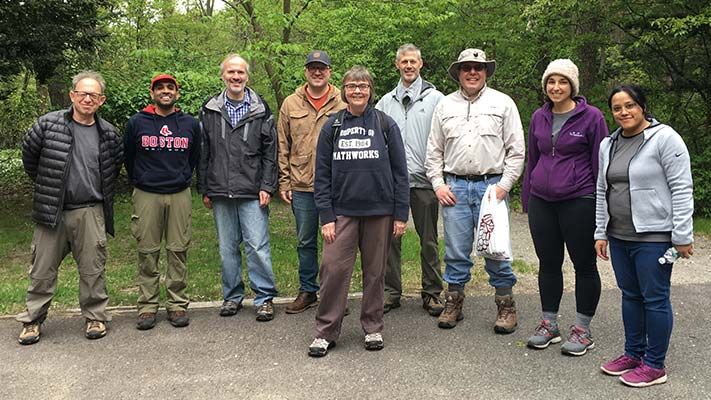 Group of nine MathWorks staff standing on a sidewalk with trees behind them