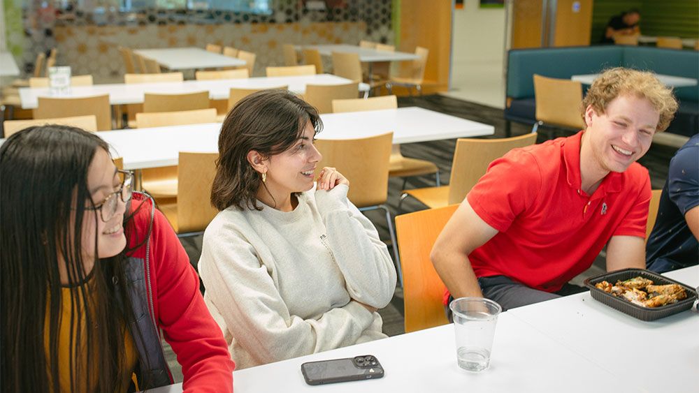Three interns laughing at lunch in the cafeteria.