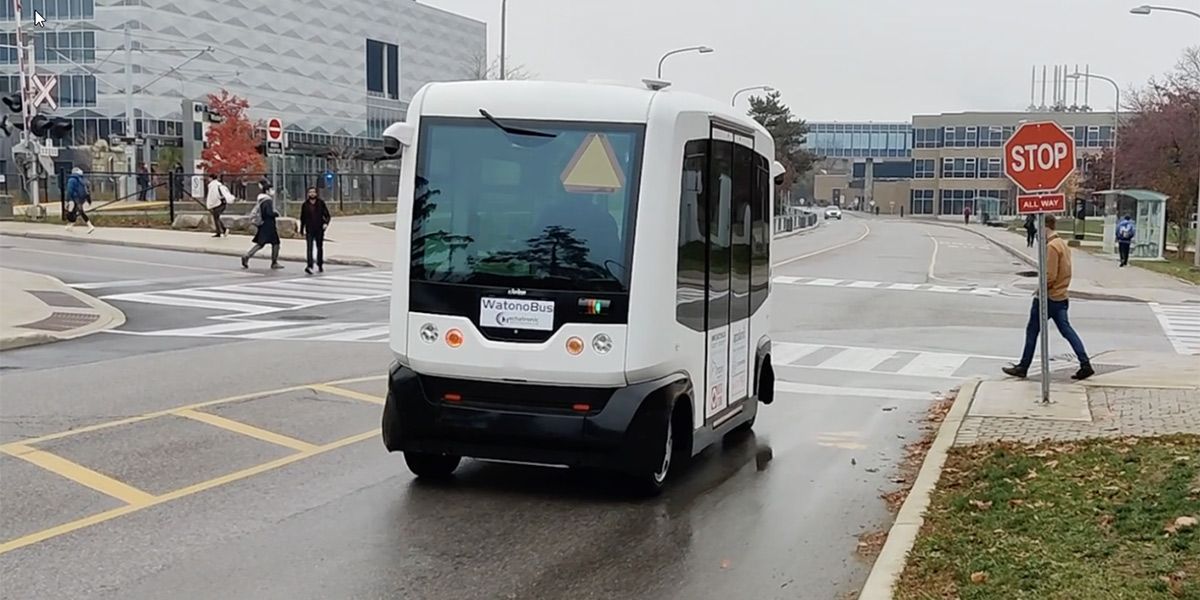 The self-driving WATonoBus stopped at an intersection to let a man on a crosswalk cross in front of the bus.