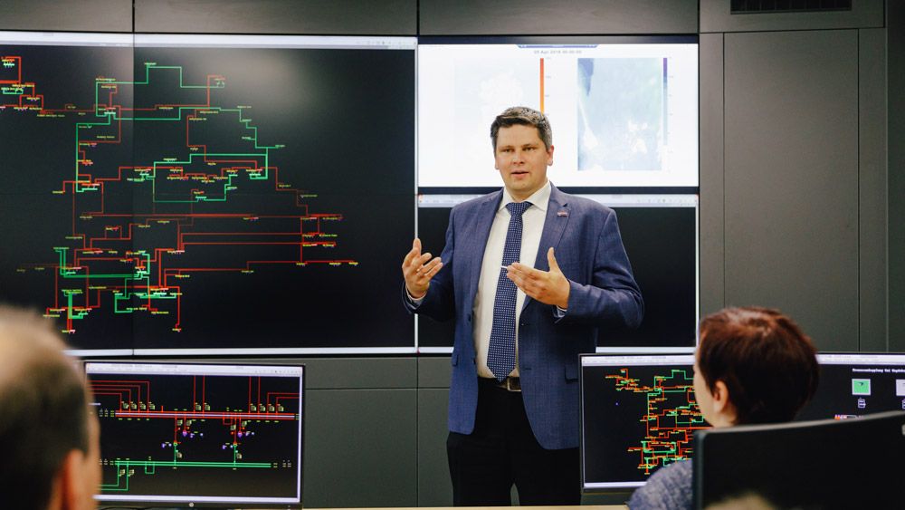 Professor Martin Wolter lecturing with a power grid optimization diagram as his students watch